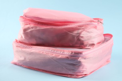 Photo of Packing cubes with clothes on light blue background, closeup