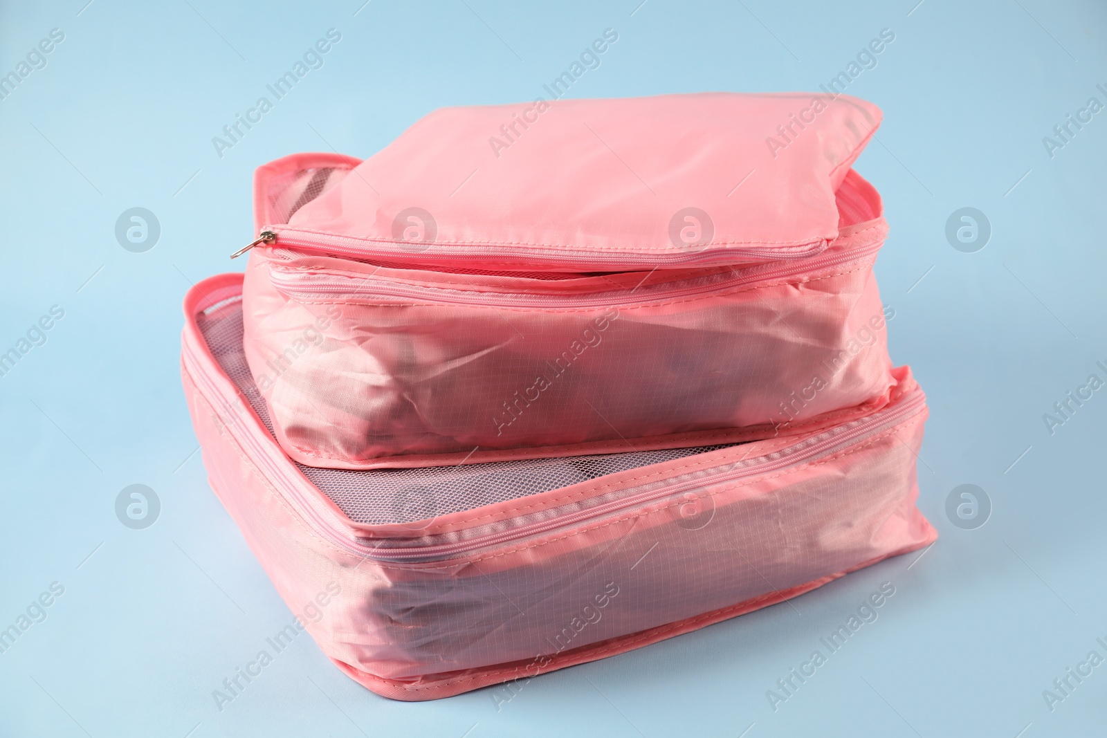 Packing cubes with clothes on light blue background, closeup Photo of Packing cubes with clothes on light blue background, closeup