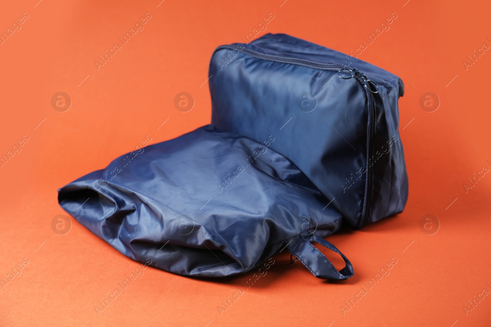Packing cubes with clothes on bright orange background, closeup Photo of Packing cubes with clothes on bright orange background, closeup