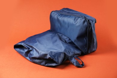 Photo of Packing cubes with clothes on bright orange background, closeup