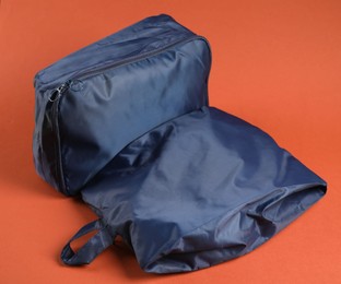 Photo of Packing cubes with clothes on bright orange background, closeup