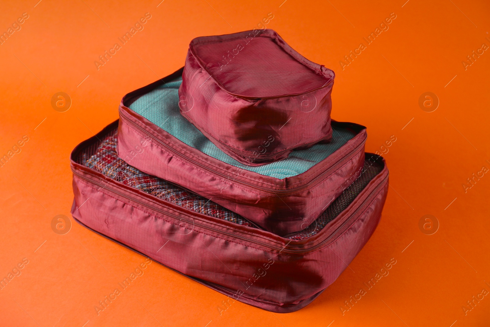 Packing cubes with clothes on bright orange background, closeup Photo of Packing cubes with clothes on bright orange background, closeup