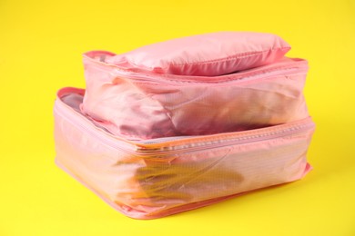 Photo of Packing cubes with clothes on yellow background, closeup