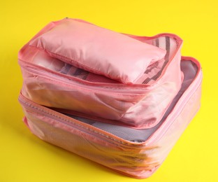 Photo of Packing cubes with clothes on yellow background, closeup