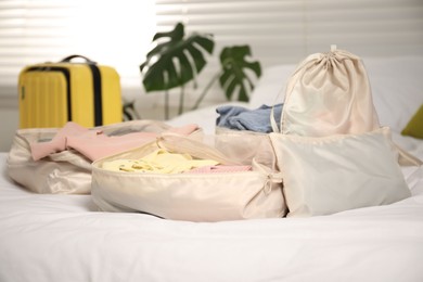 Photo of Packing cubes with clothes on bed indoors, closeup