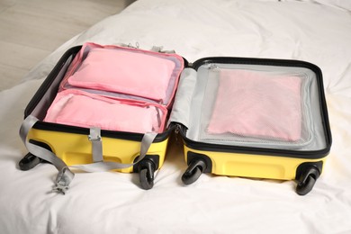 Photo of Open suitcase with packing cubes on bed indoors