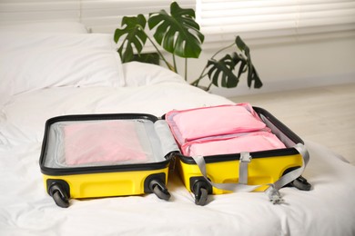 Photo of Open suitcase with packing cubes on bed indoors