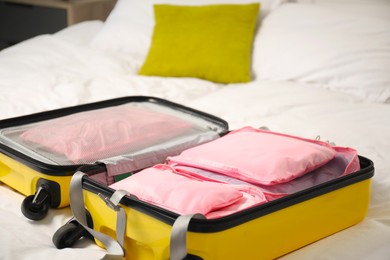 Photo of Open suitcase with packing cubes on bed indoors, closeup
