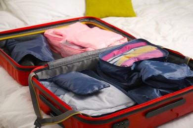 Photo of Open suitcase with packing cubes on bed indoors, closeup