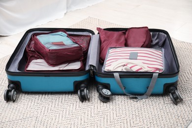 Photo of Open suitcase with packing cubes on floor indoors