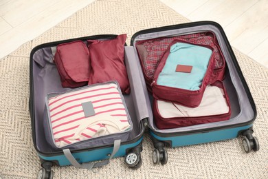 Photo of Open suitcase with packing cubes on floor indoors, above view