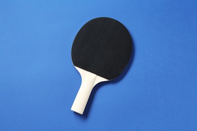 Photo of One ping pong racket on blue background, top view