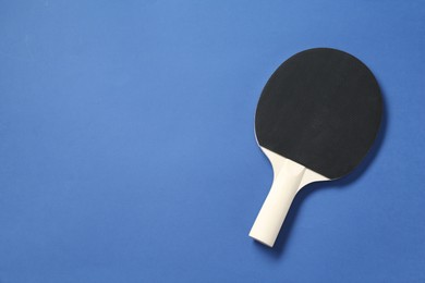 Photo of One ping pong racket on blue background, top view. Space for text
