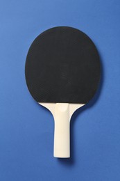 Photo of One ping pong racket on blue background, top view