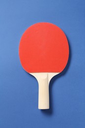 Photo of One ping pong racket on blue background, top view