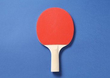 Photo of One ping pong racket on blue background, top view