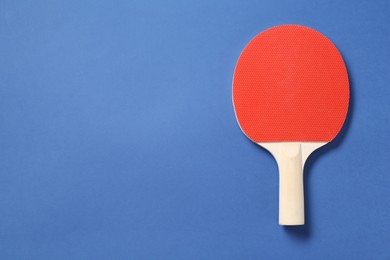 Photo of One ping pong racket on blue background, top view. Space for text