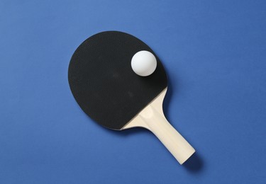 Photo of Ping pong racket and ball on blue background, top view
