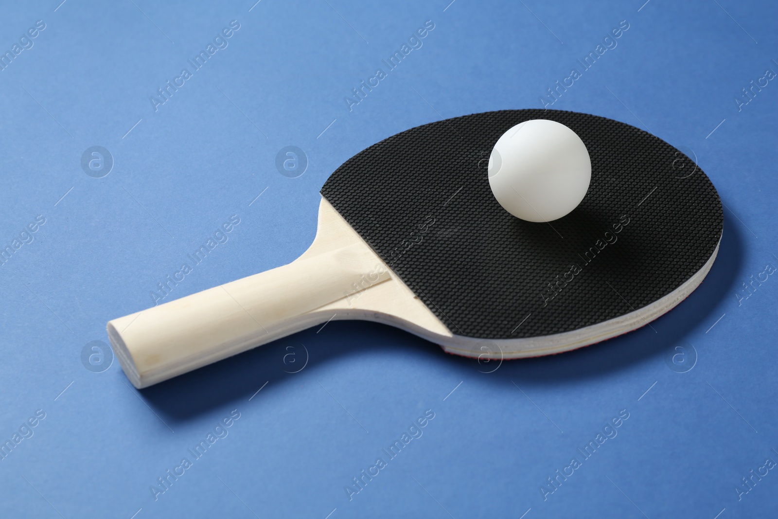Ping pong racket and ball on blue background, closeup Photo of Ping pong racket and ball on blue background, closeup