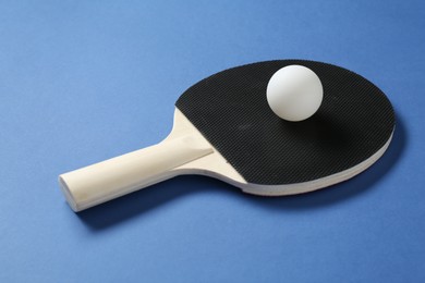 Photo of Ping pong racket and ball on blue background, closeup