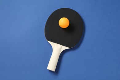 Photo of Ping pong racket and ball on blue background, top view