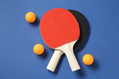 Photo of Ping pong rackets and balls on blue background, top view