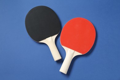 Photo of Ping pong rackets on blue background, top view