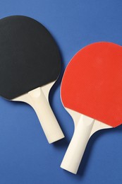 Photo of Ping pong rackets on blue background, top view