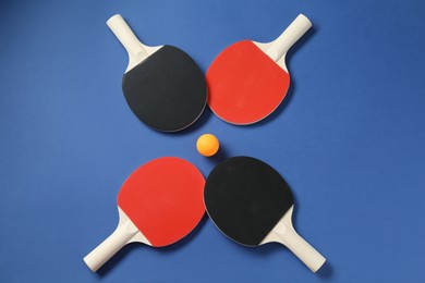 Photo of Ping pong rackets and ball on blue background, flat lay