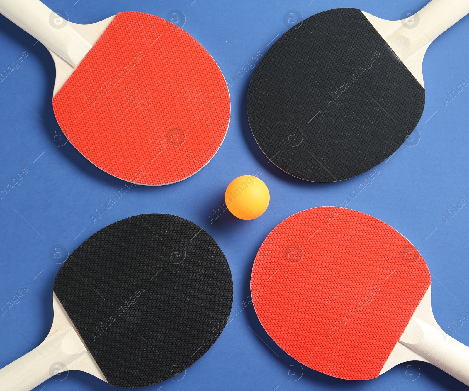 Ping pong rackets and ball on blue background, flat lay Photo of Ping pong rackets and ball on blue background, flat lay