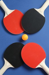 Photo of Ping pong rackets and ball on blue background, flat lay
