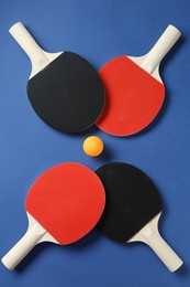 Photo of Ping pong rackets and ball on blue background, flat lay