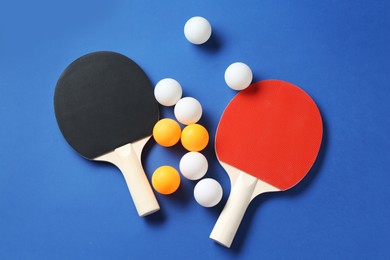 Photo of Ping pong rackets and balls on blue background, flat lay