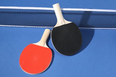 Photo of Ping pong rackets and net on blue background