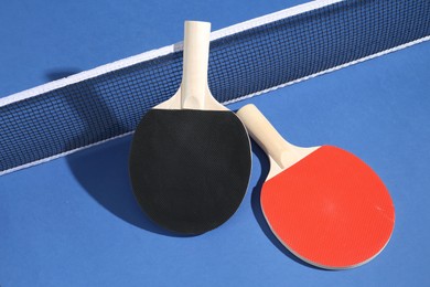Photo of Ping pong rackets and net on blue background