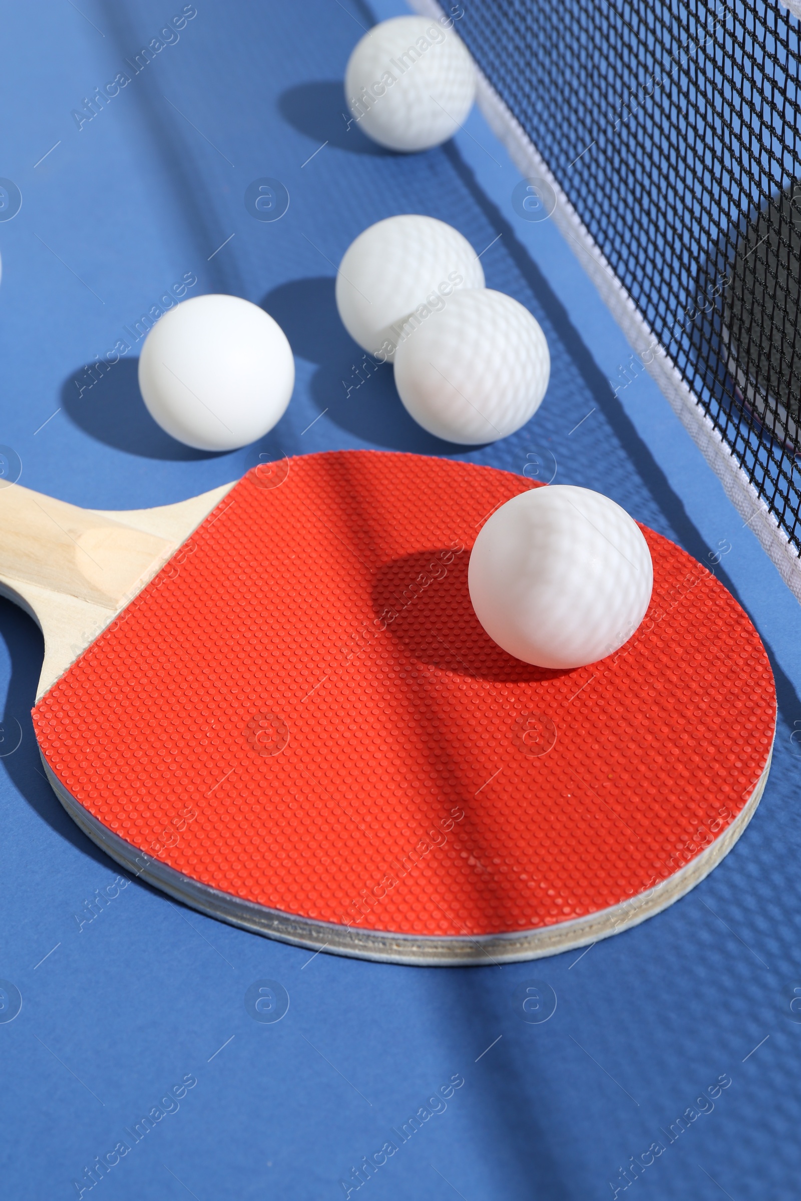 Ping pong racket, balls and net on blue background, closeup Photo of Ping pong racket, balls and net on blue background, closeup