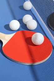 Photo of Ping pong racket, balls and net on blue background, closeup