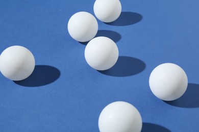 Photo of Many ping pong balls on blue background, closeup