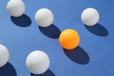 Photo of Many ping pong balls on blue background, closeup