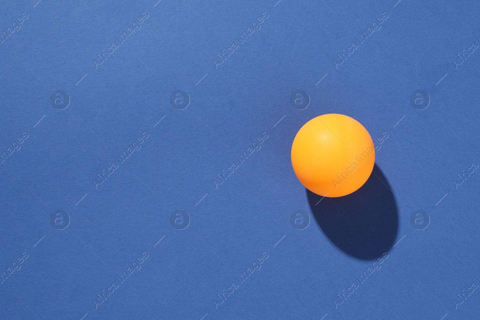 One ping pong ball on blue background, top view. Space for text Photo of One ping pong ball on blue background, top view. Space for text