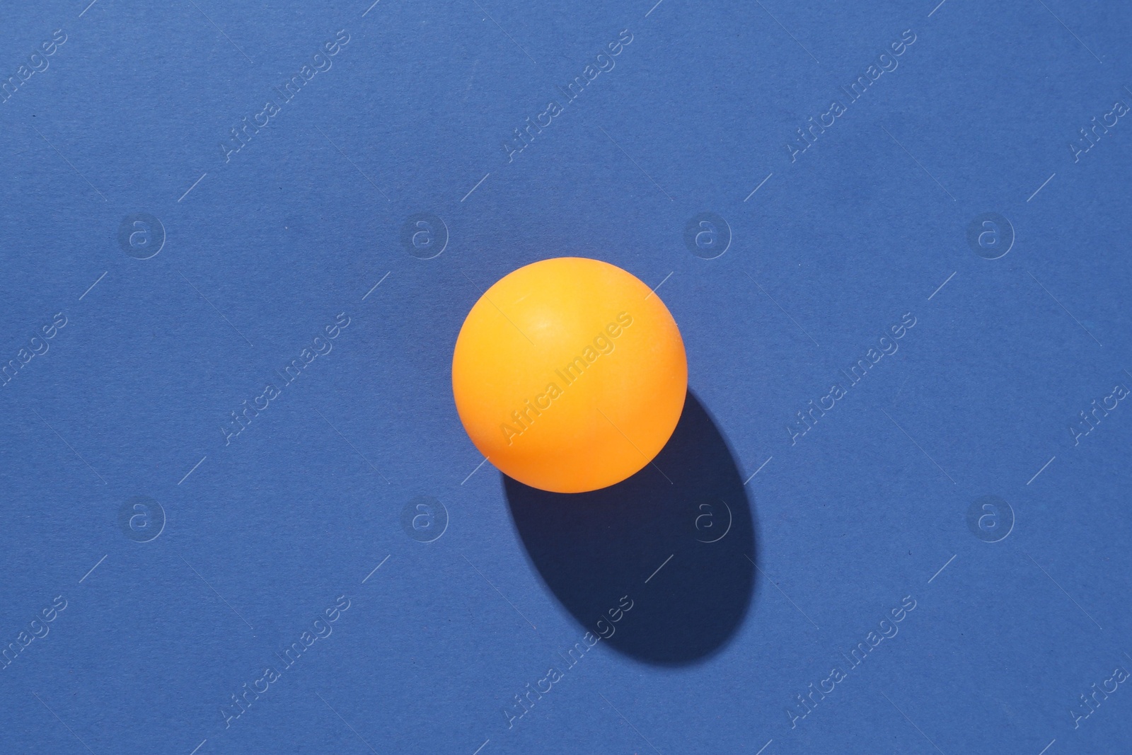 One ping pong ball on blue background, top view Photo of One ping pong ball on blue background, top view