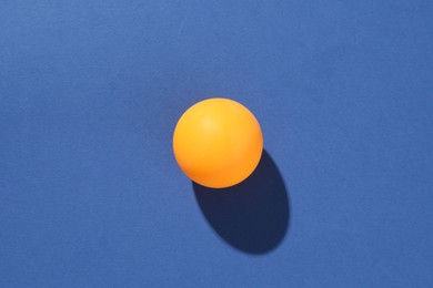 Photo of One ping pong ball on blue background, top view