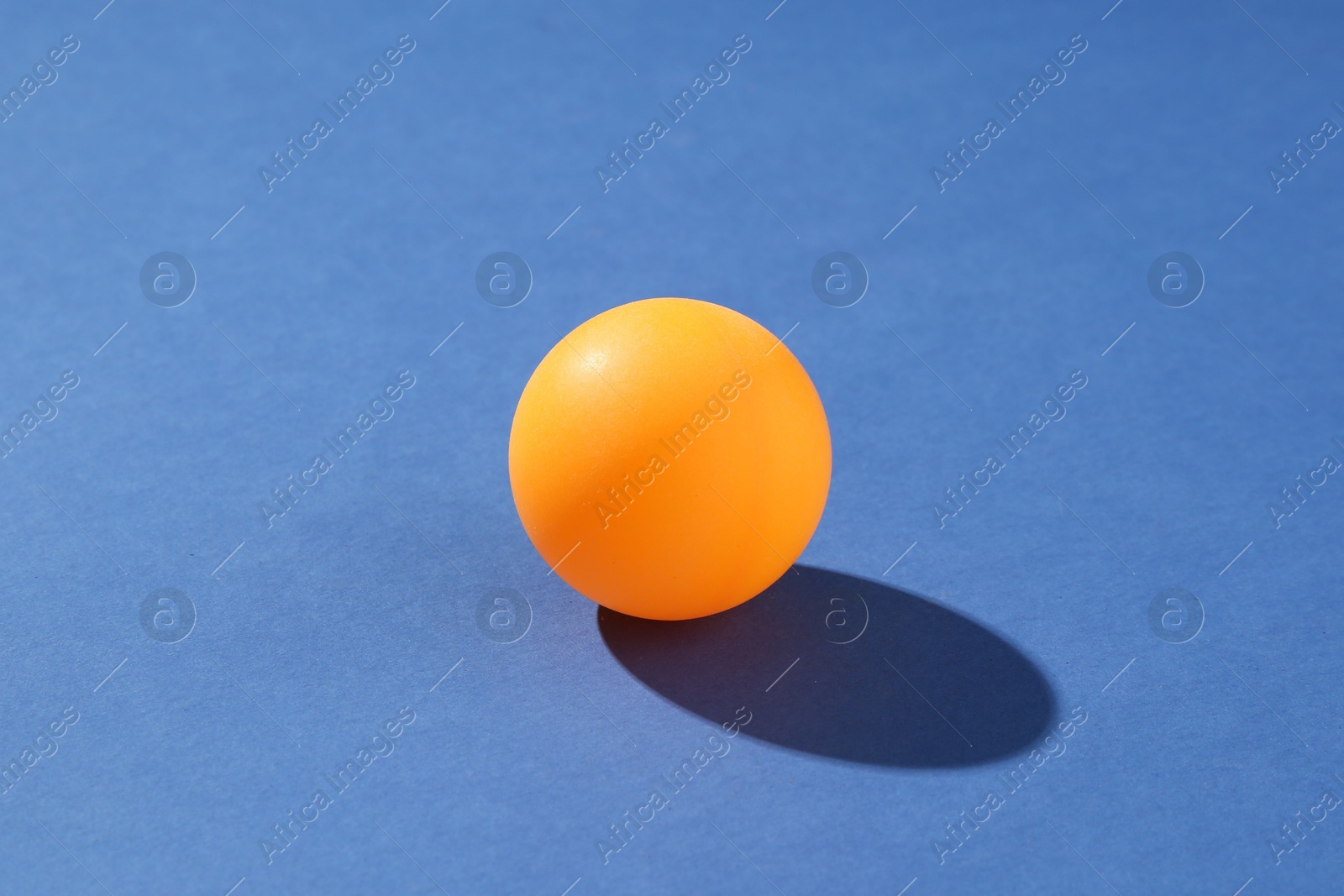 One ping pong ball on blue background, closeup Photo of One ping pong ball on blue background, closeup
