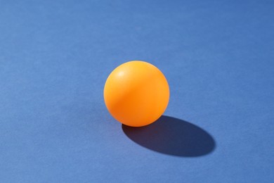 Photo of One ping pong ball on blue background, closeup