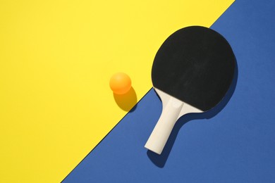 Photo of Ping pong racket and ball on color background, top view. Space for text