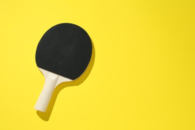 Photo of One ping pong racket on yellow background, top view. Space for text