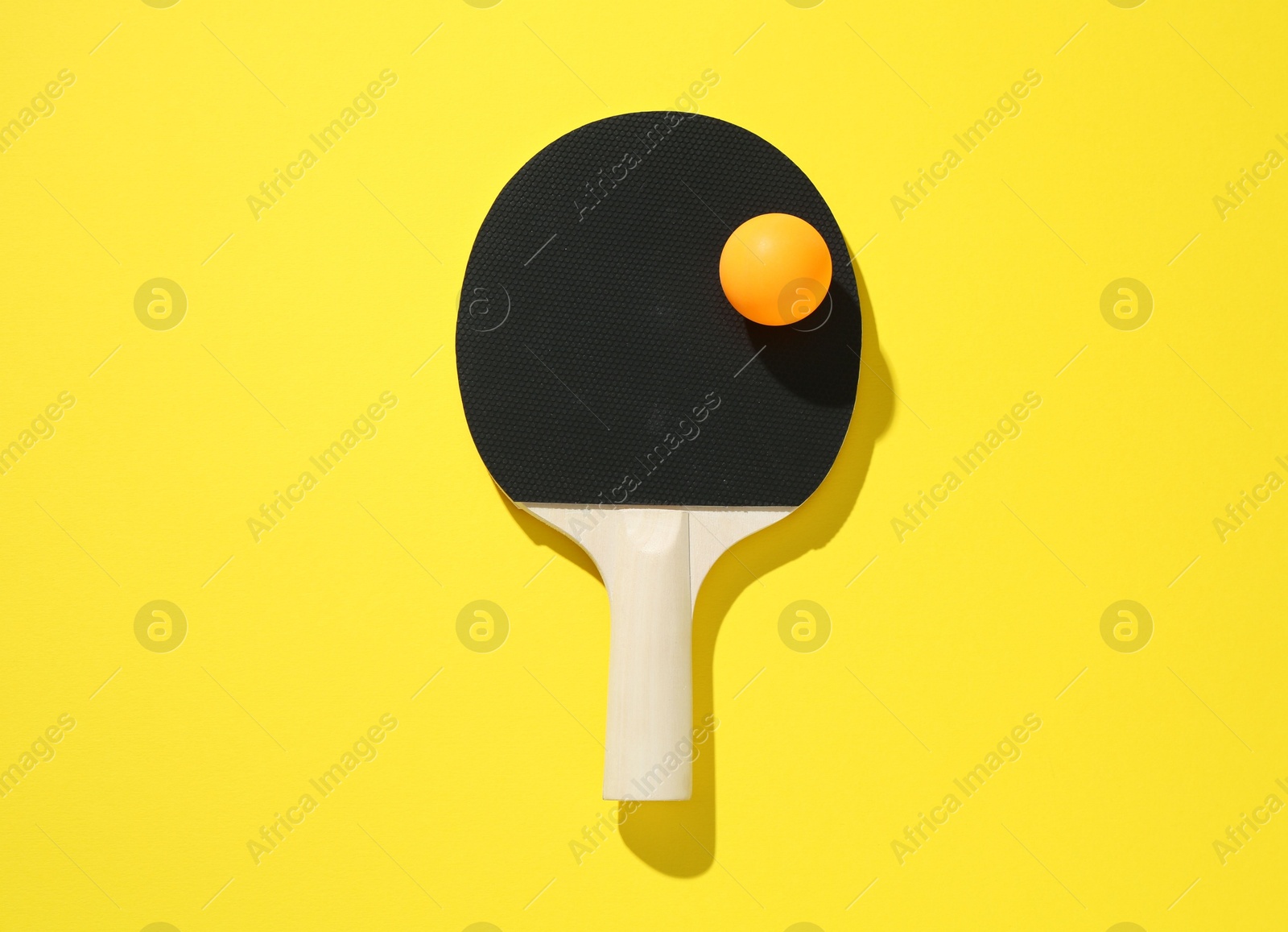 Ping pong racket and ball on yellow background, top view Photo of Ping pong racket and ball on yellow background, top view