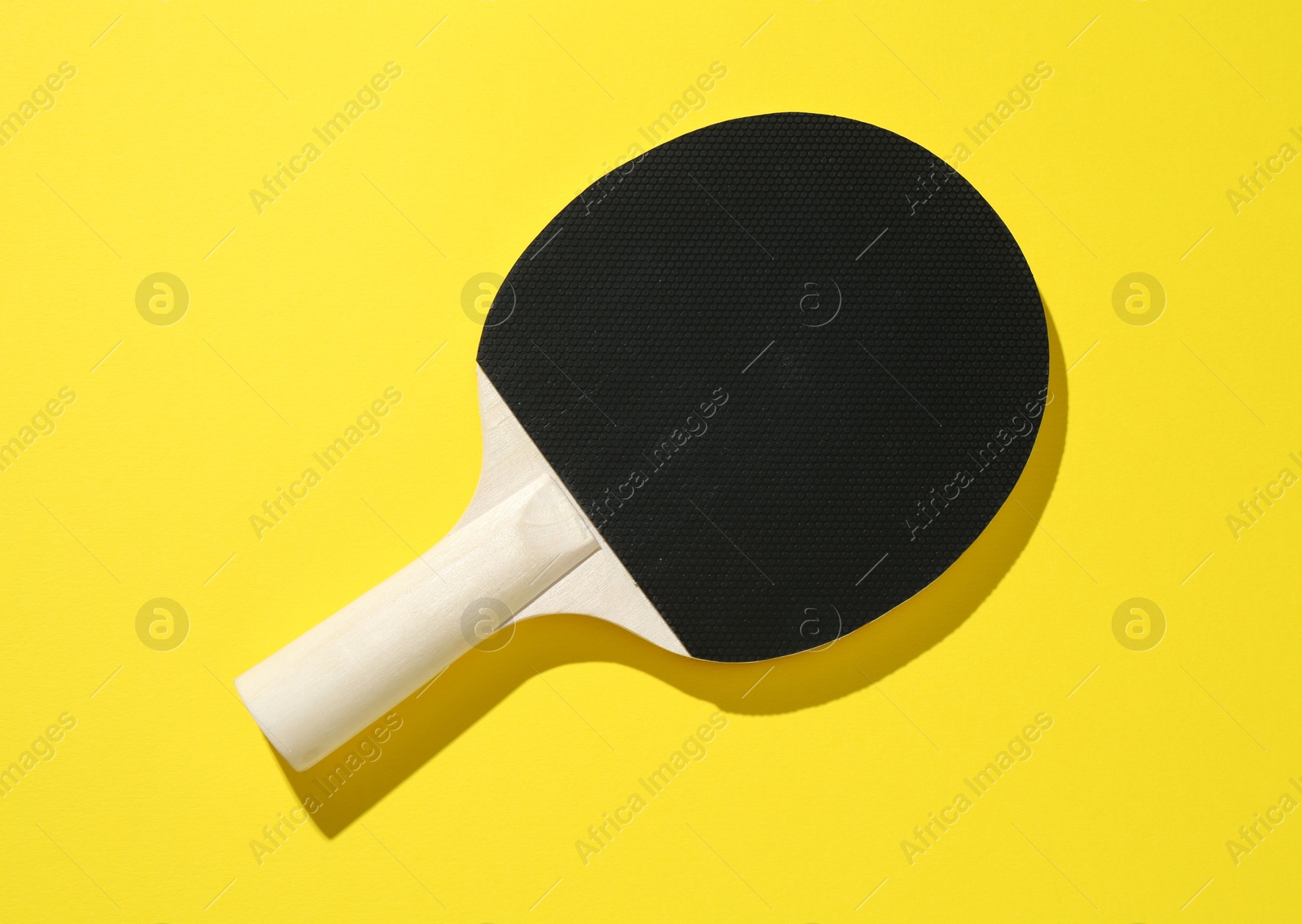 One ping pong racket on yellow background, top view Photo of One ping pong racket on yellow background, top view