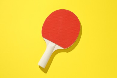 Photo of One ping pong racket on yellow background, top view