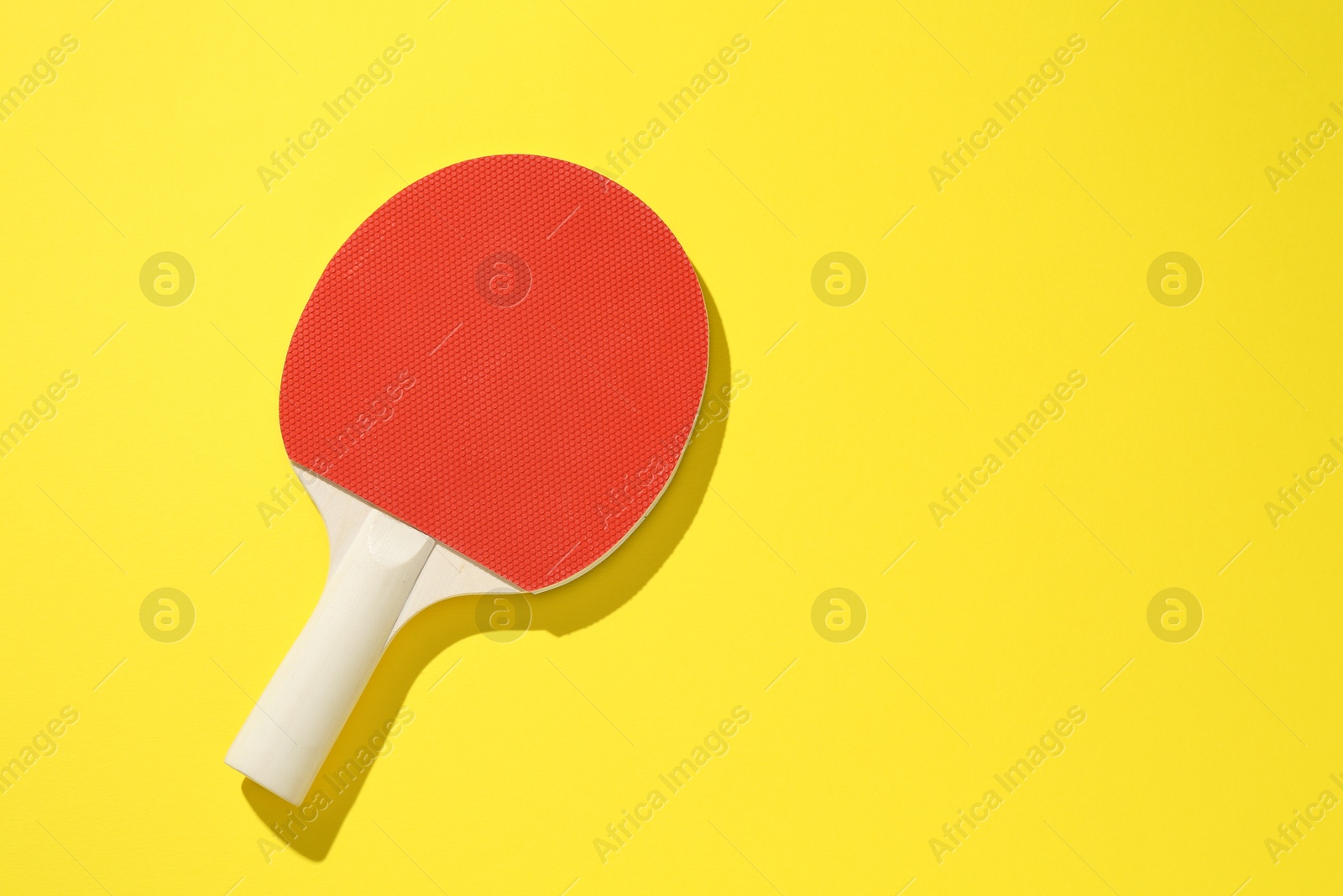 One ping pong racket on yellow background, top view. Space for text Photo of One ping pong racket on yellow background, top view. Space for text